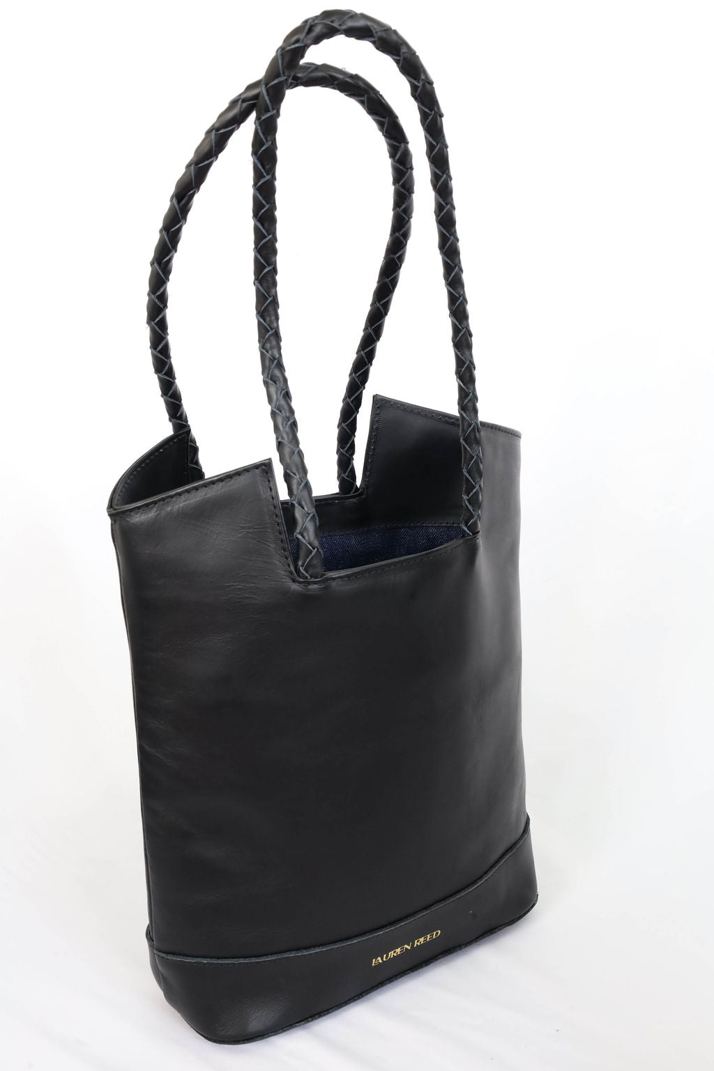 Black leather tote bag with braided handles on a white background