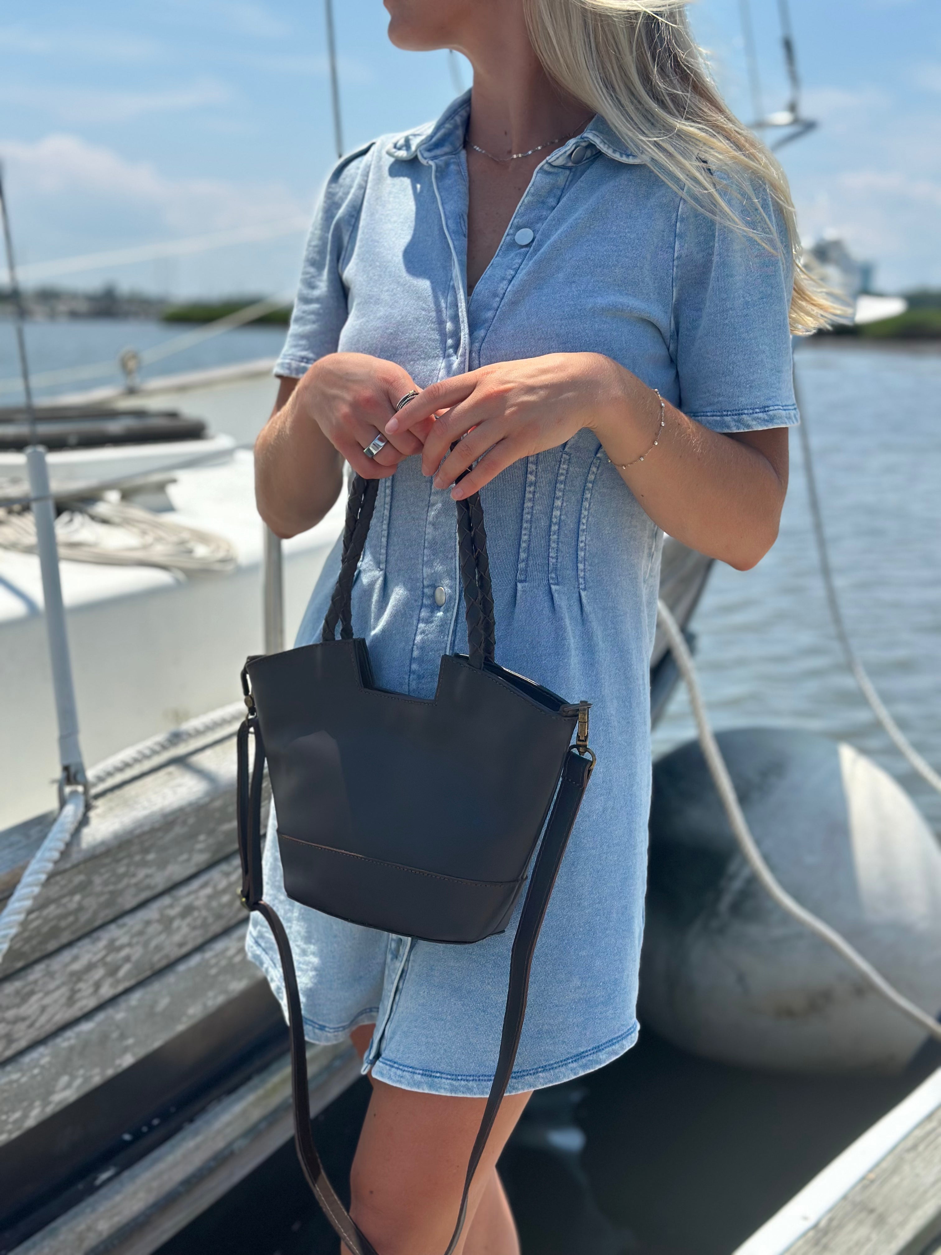 Woman holding a brown handbag on a boat with water and sky in the background