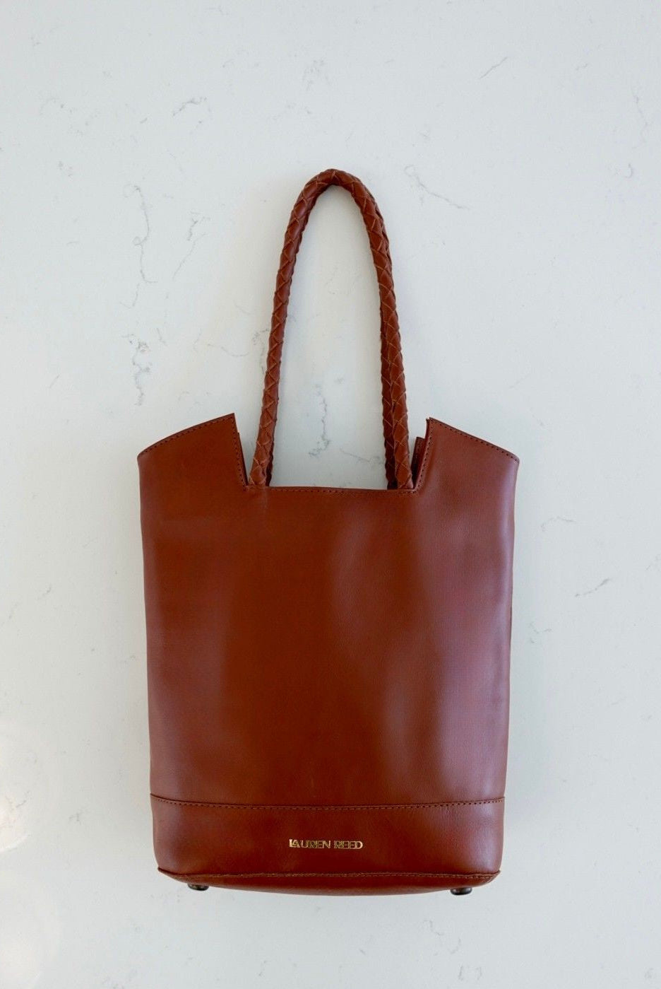 Brown leather tote bag branded Lauren Reed on a white background