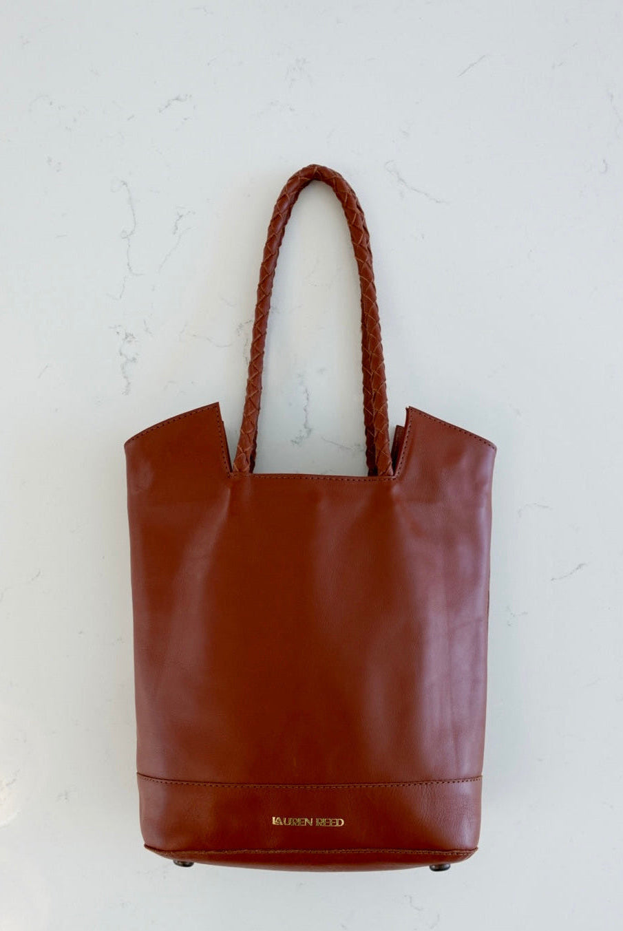 Saddle tan leather tote bag purse on marble