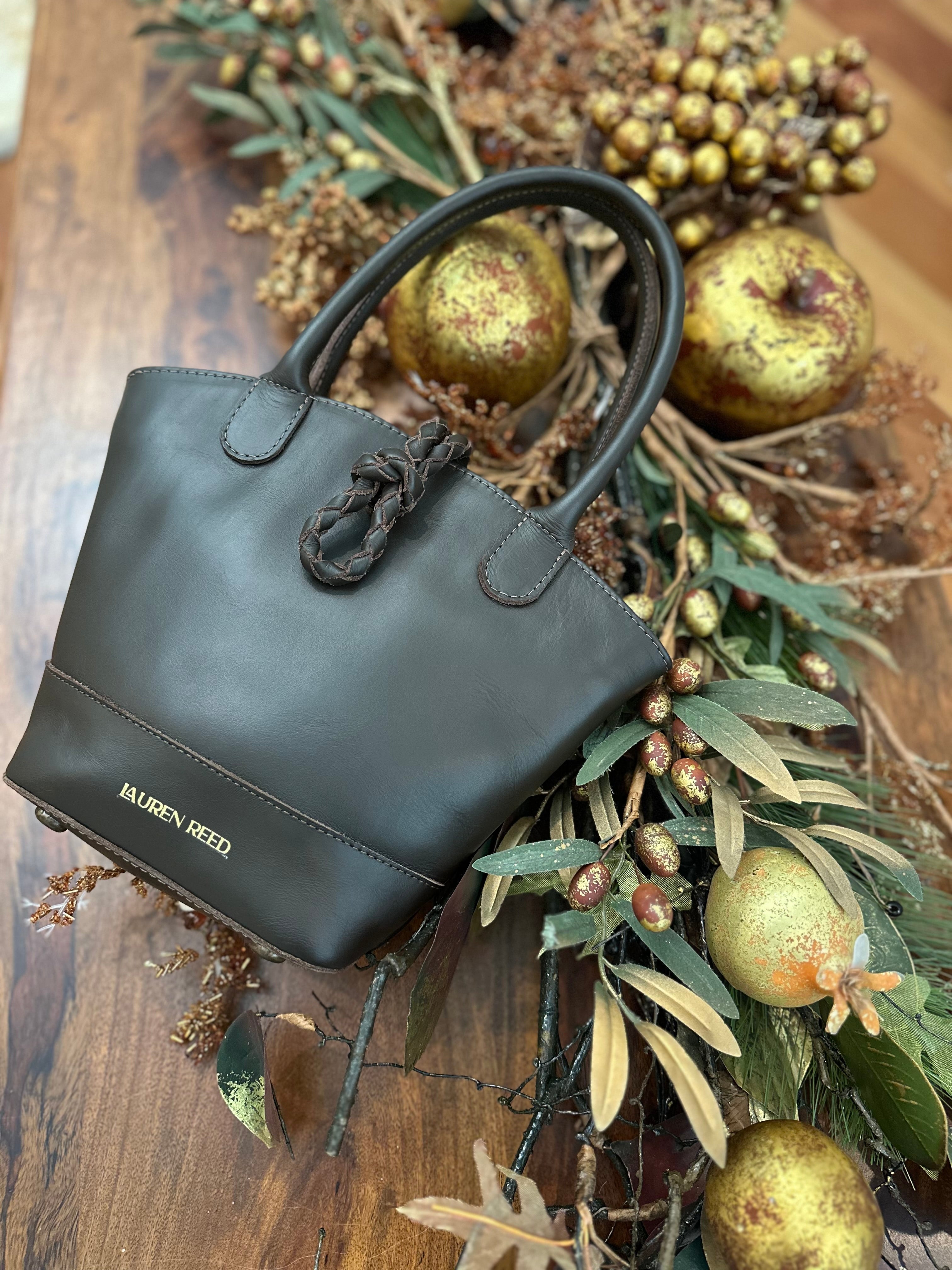 Black handbag on a wooden surface with greenery