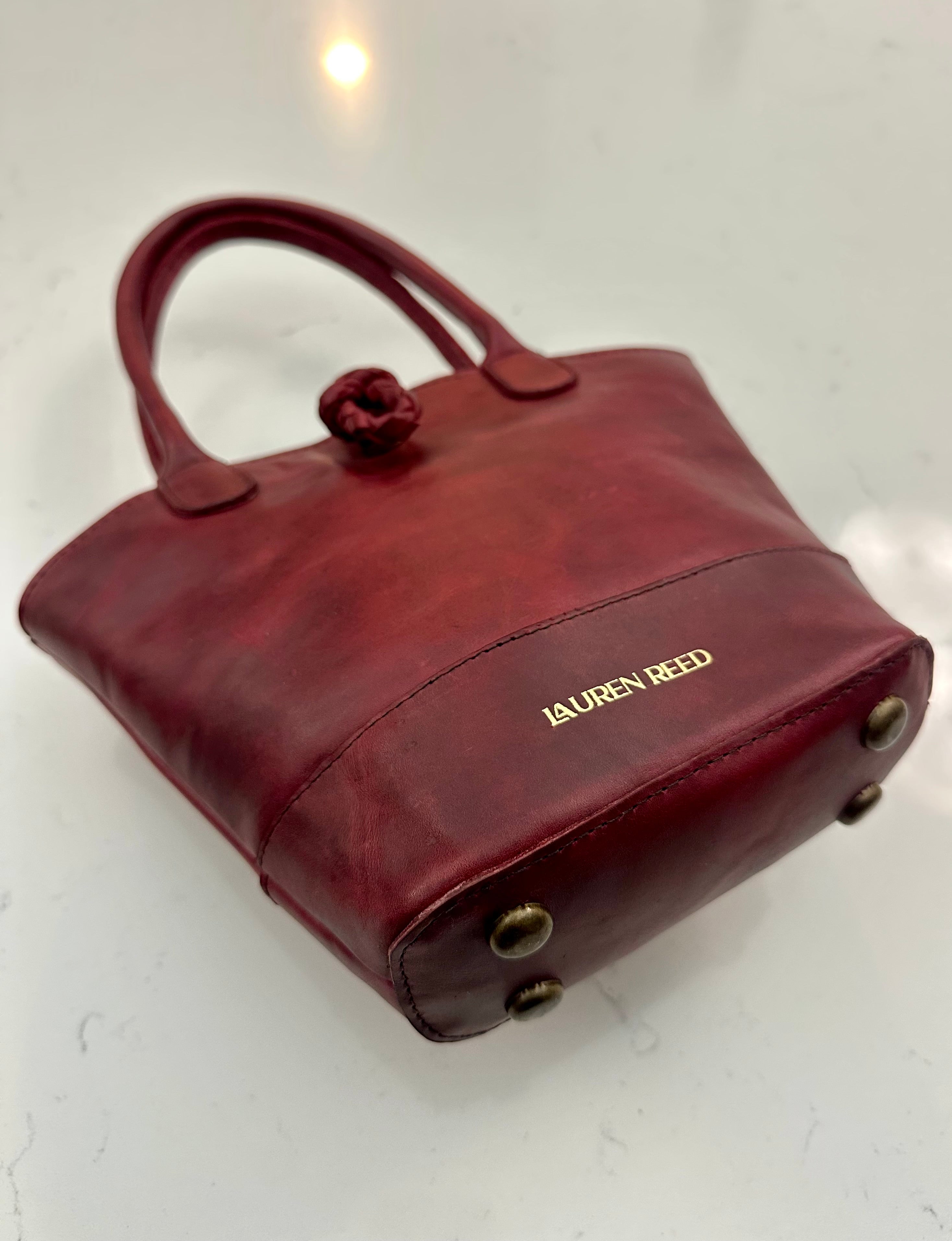 Red handbag with 'Lauren Reed' branding on a light background