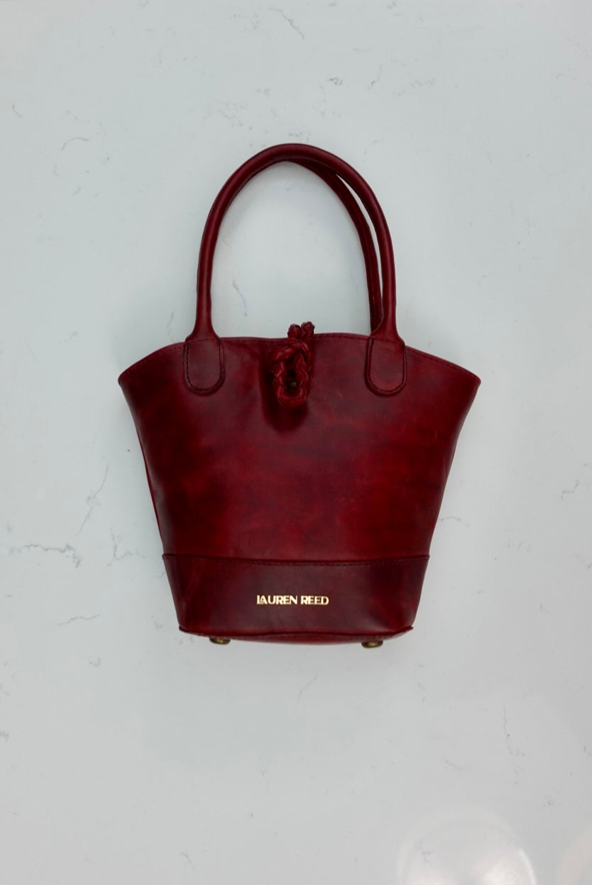 Red handbag with ‘Lauren Reed' branding on a light gray background