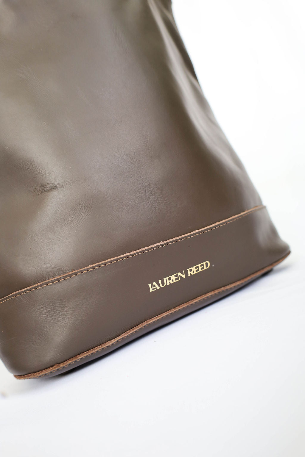 Brown leather bag with 'Lauren Reed' branding on a white background