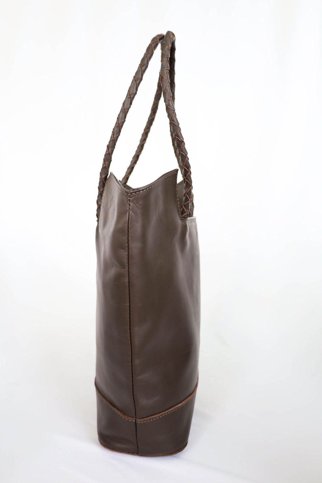 Side angle brown leather bag with braided handle on a white background