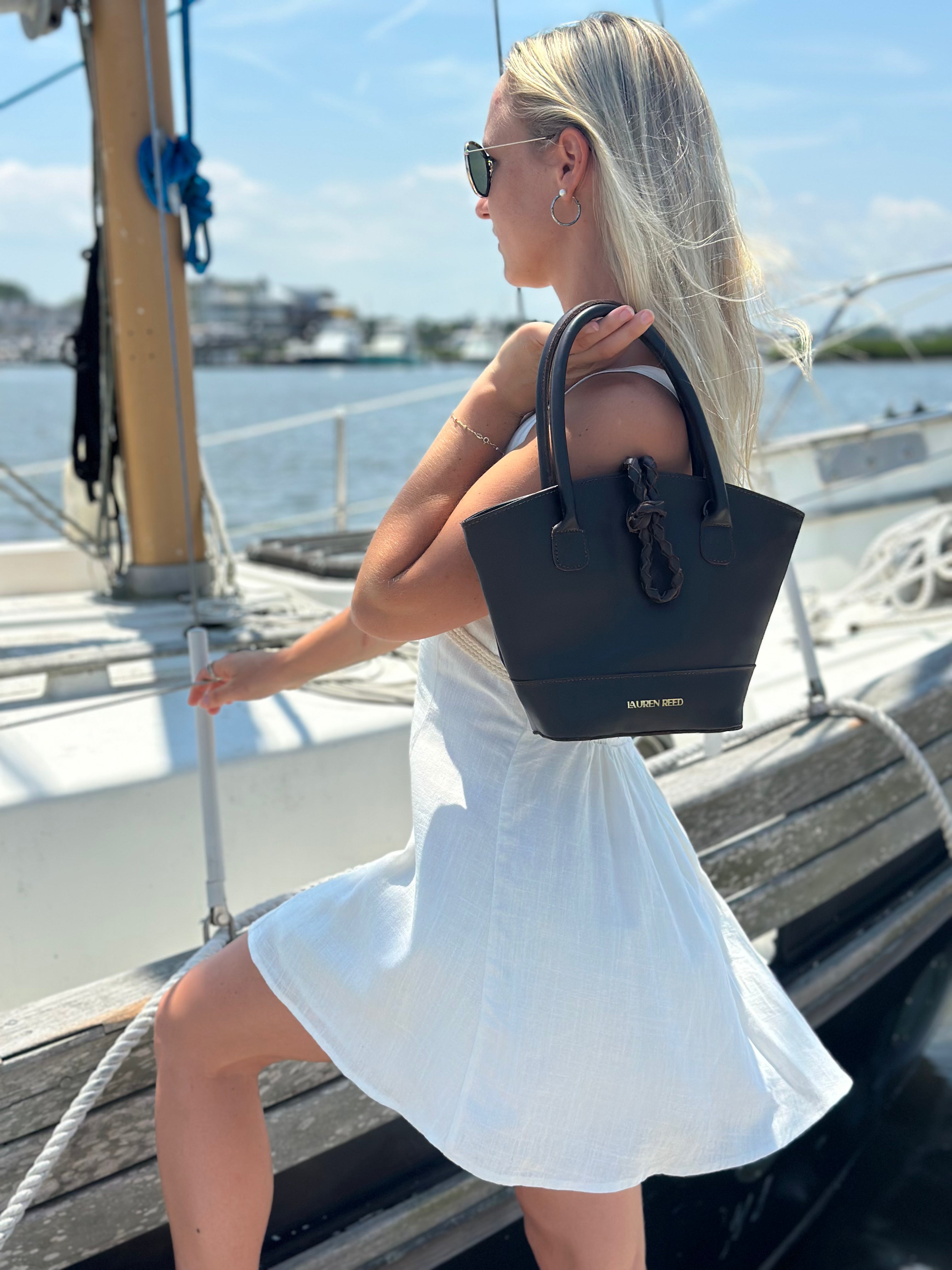 Woman in a white dress holding a brown handbag on a boat
