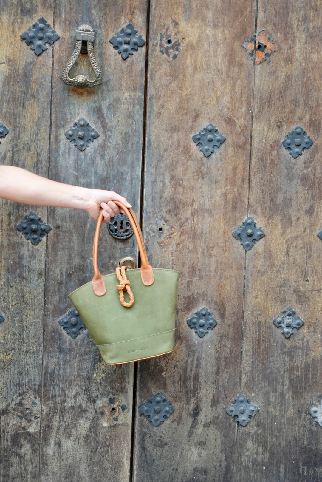 Green Leather Nubuck Purse held by wooden door