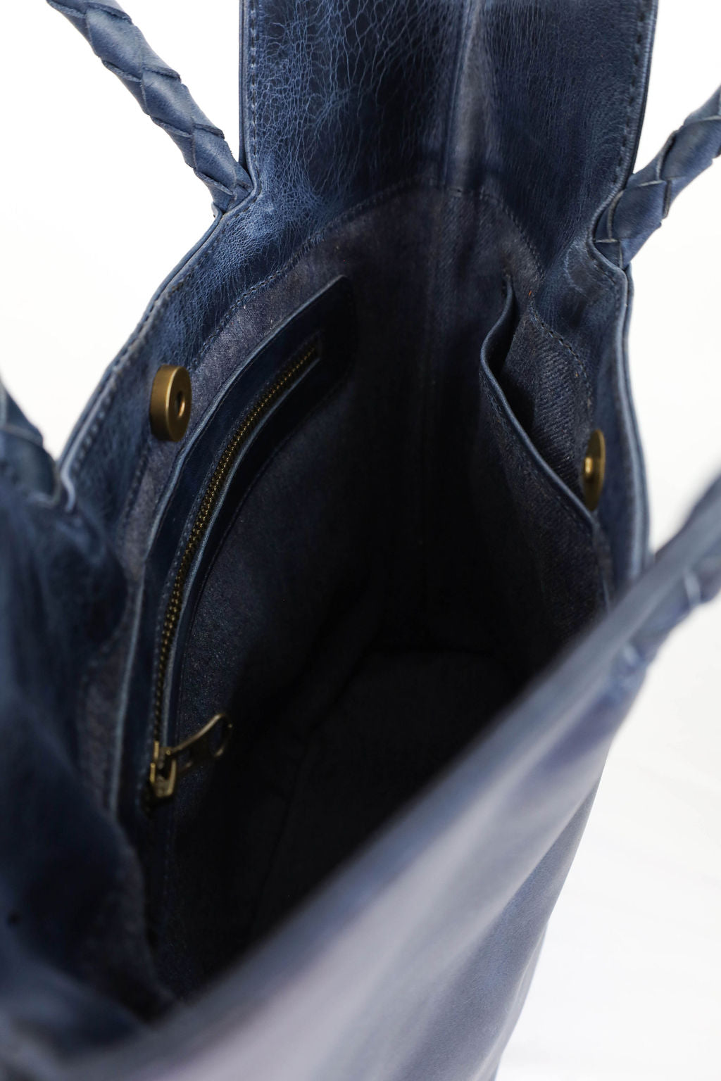 Close-up of a blue leather handbag with braided handle on a white background