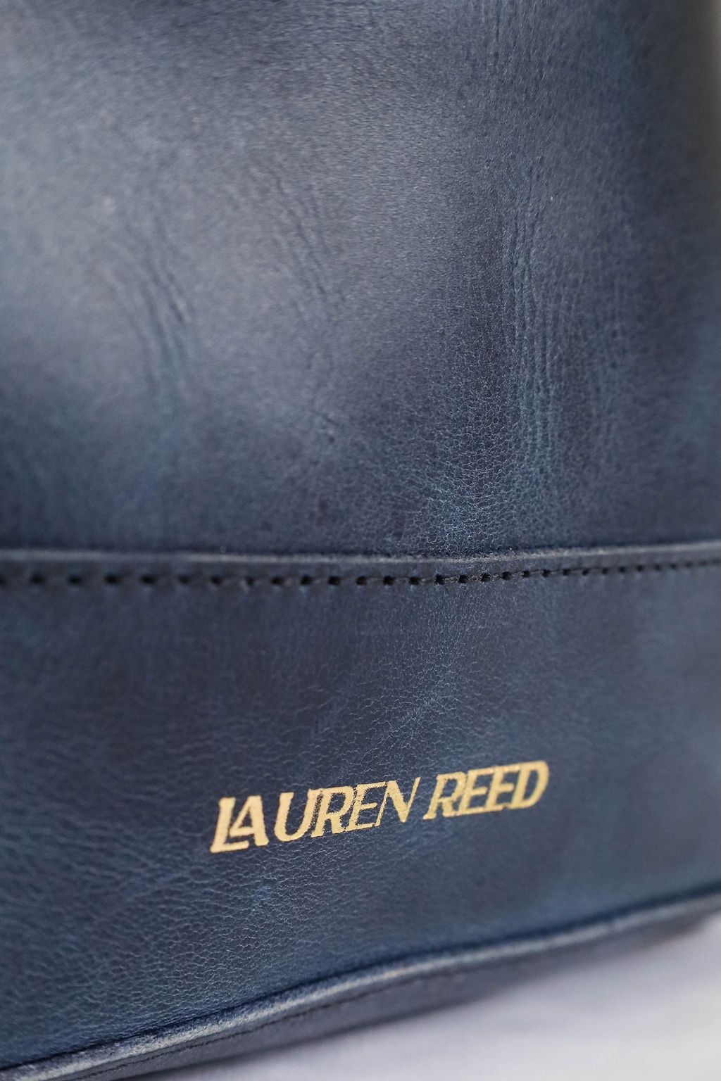 Navy blue leather bag with 'Lauren Reed' logo on a white background