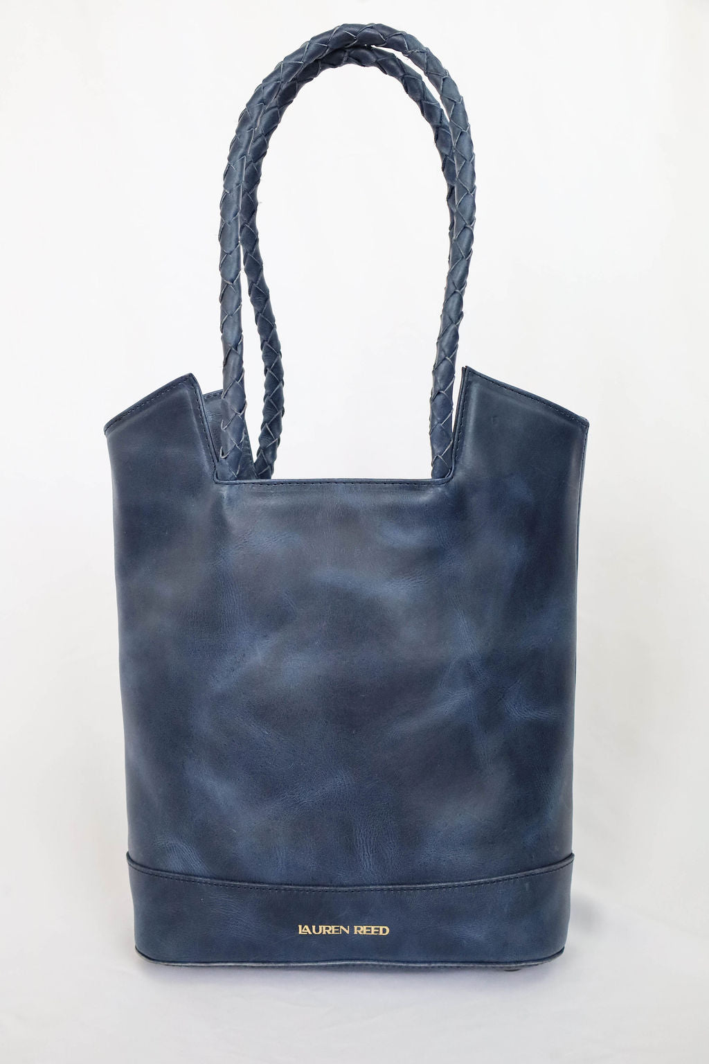 Blue leather tote bag with rope handles on a white background