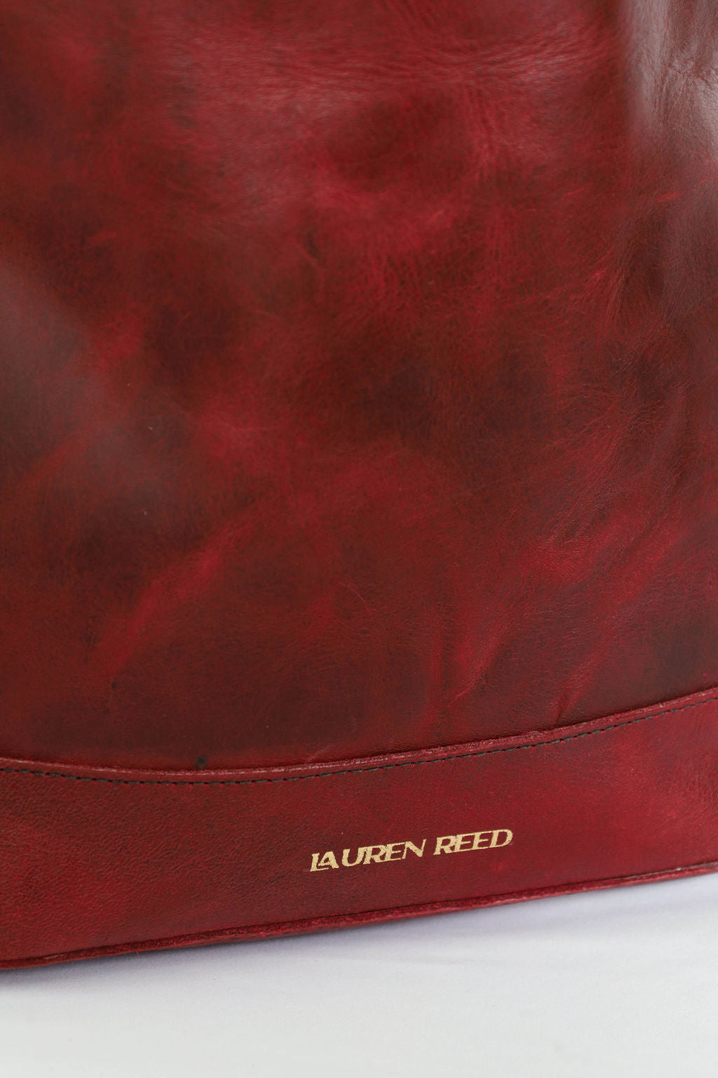 Red leather bag with 'Lauren Reed' branding on a white background