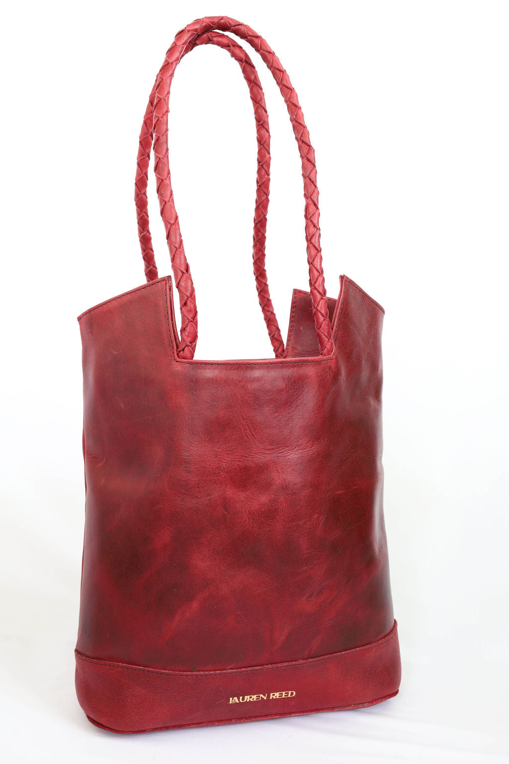 Red leather tote bag with braided handles on a white background