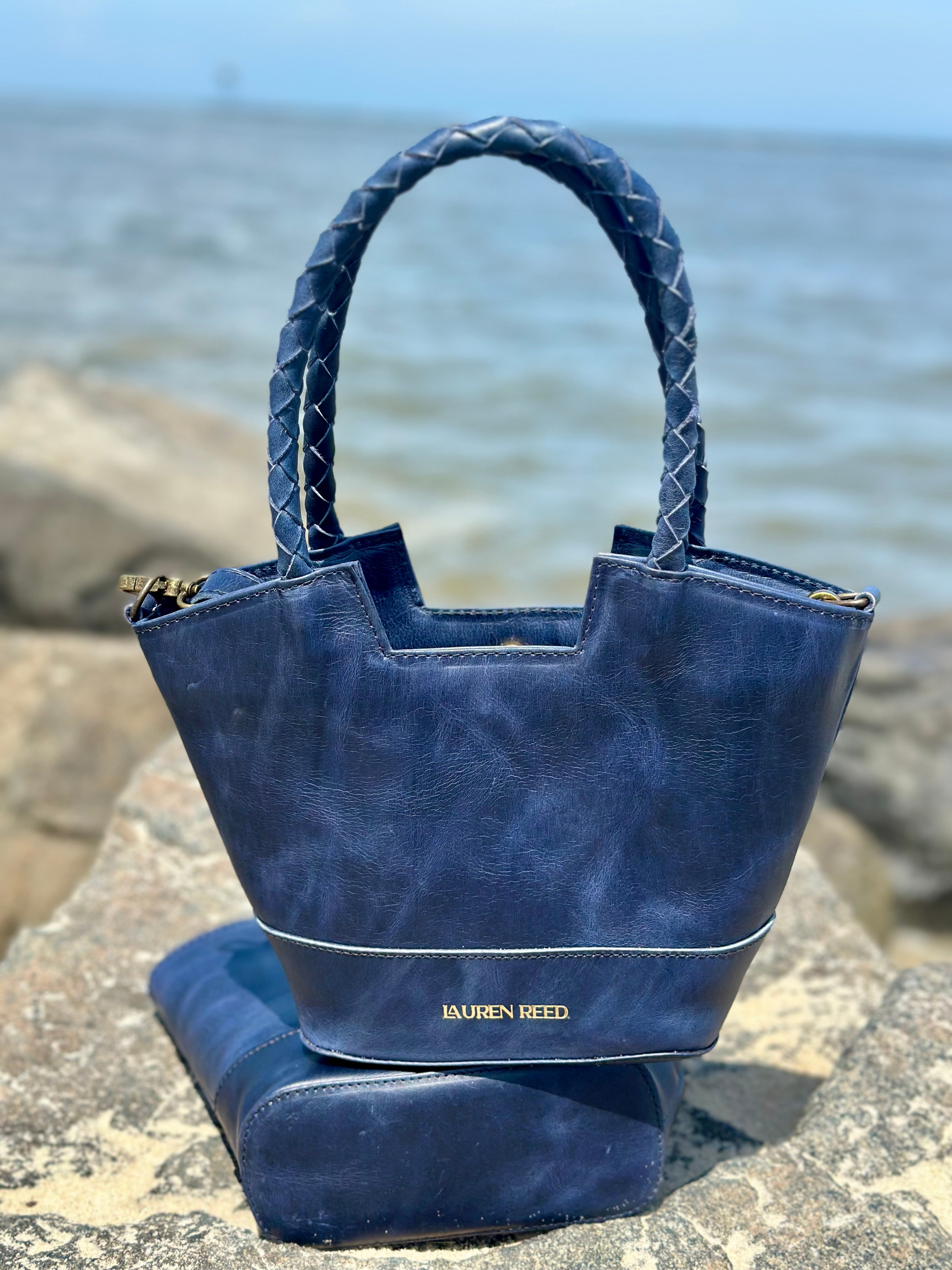 Blue handbag with matching purse on a rocky surface near water