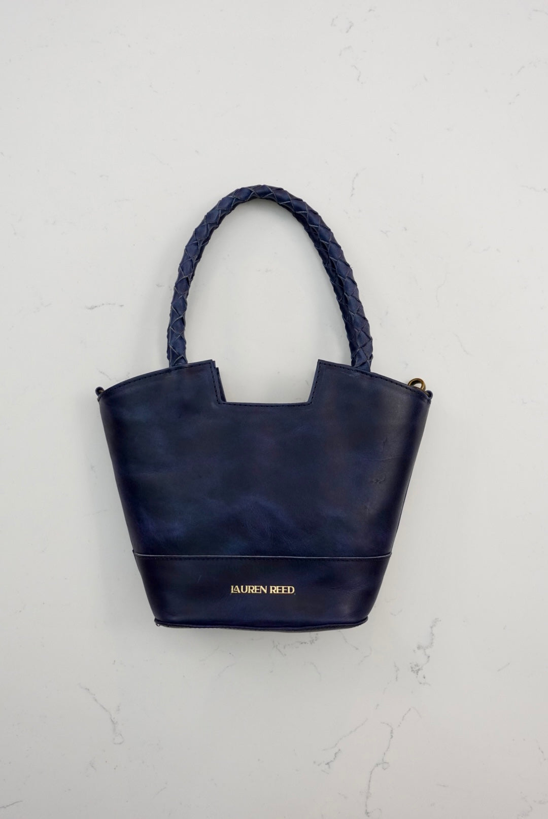 Navy blue handbag with 'Lauren Reed' branding on a light gray background