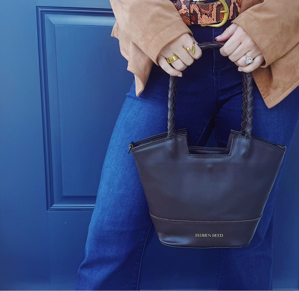 Leather handbag held by jeans.