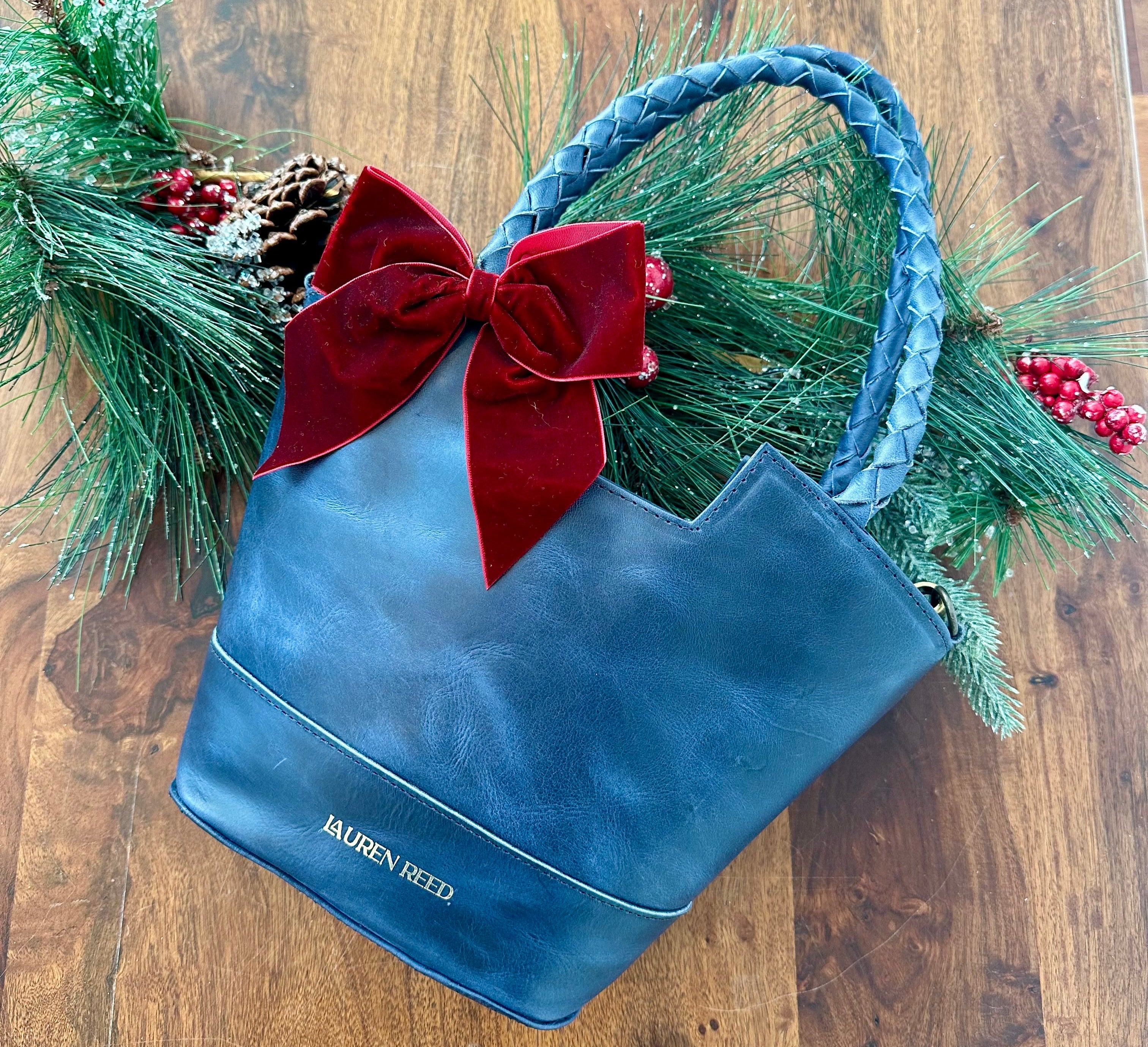 Blue handbag with a red bow and Christmas decorations on a wooden surface