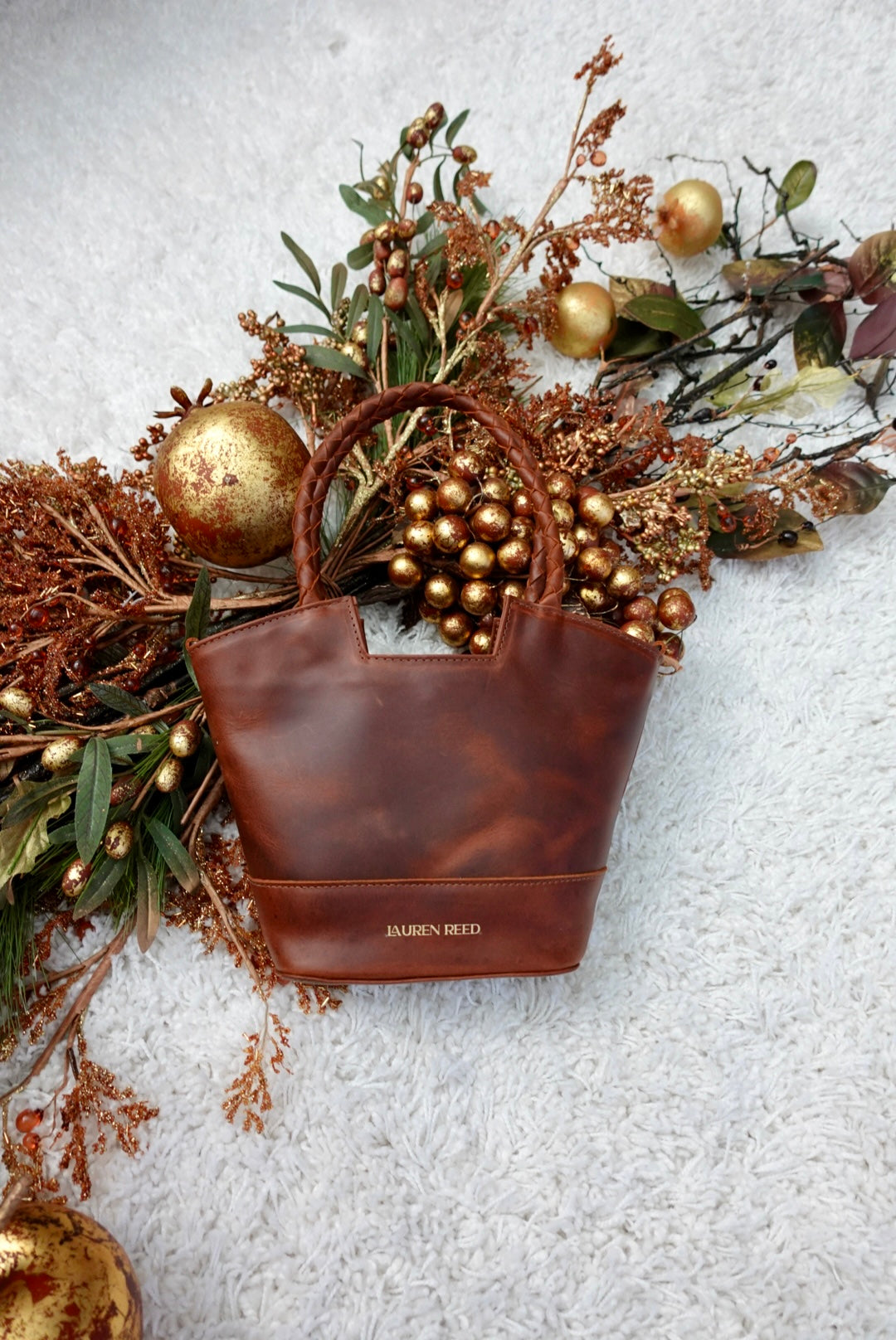 Brown leather handbag with gold accents on a textured surface with decorative elements