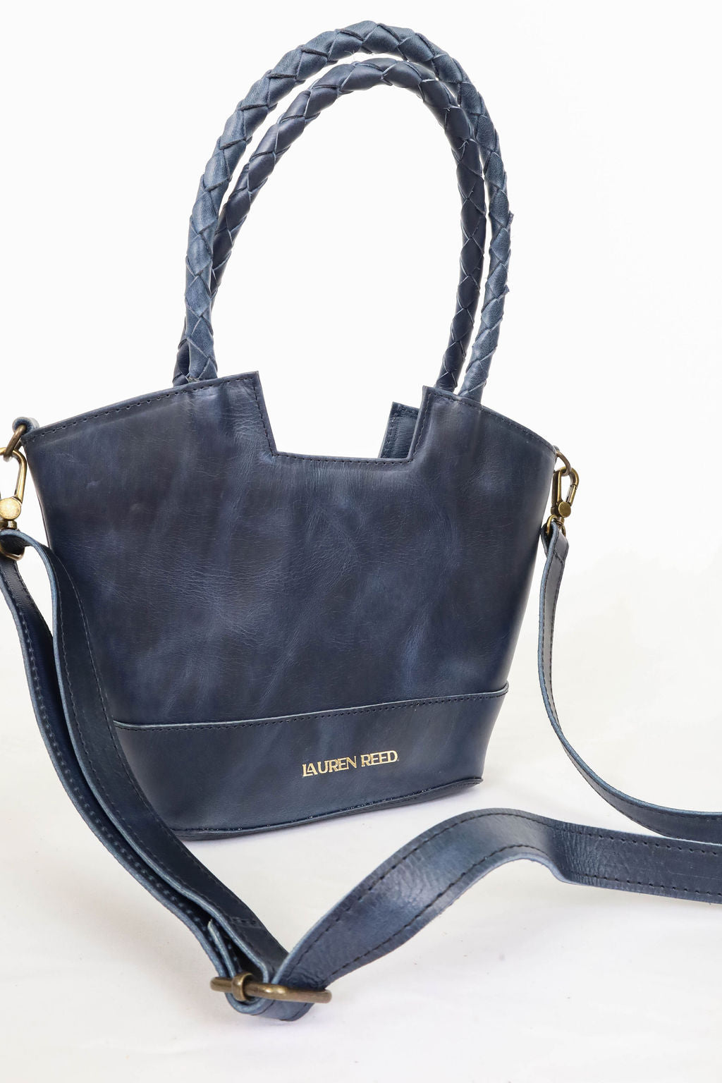 Navy blue handbag with braided handle on a white background