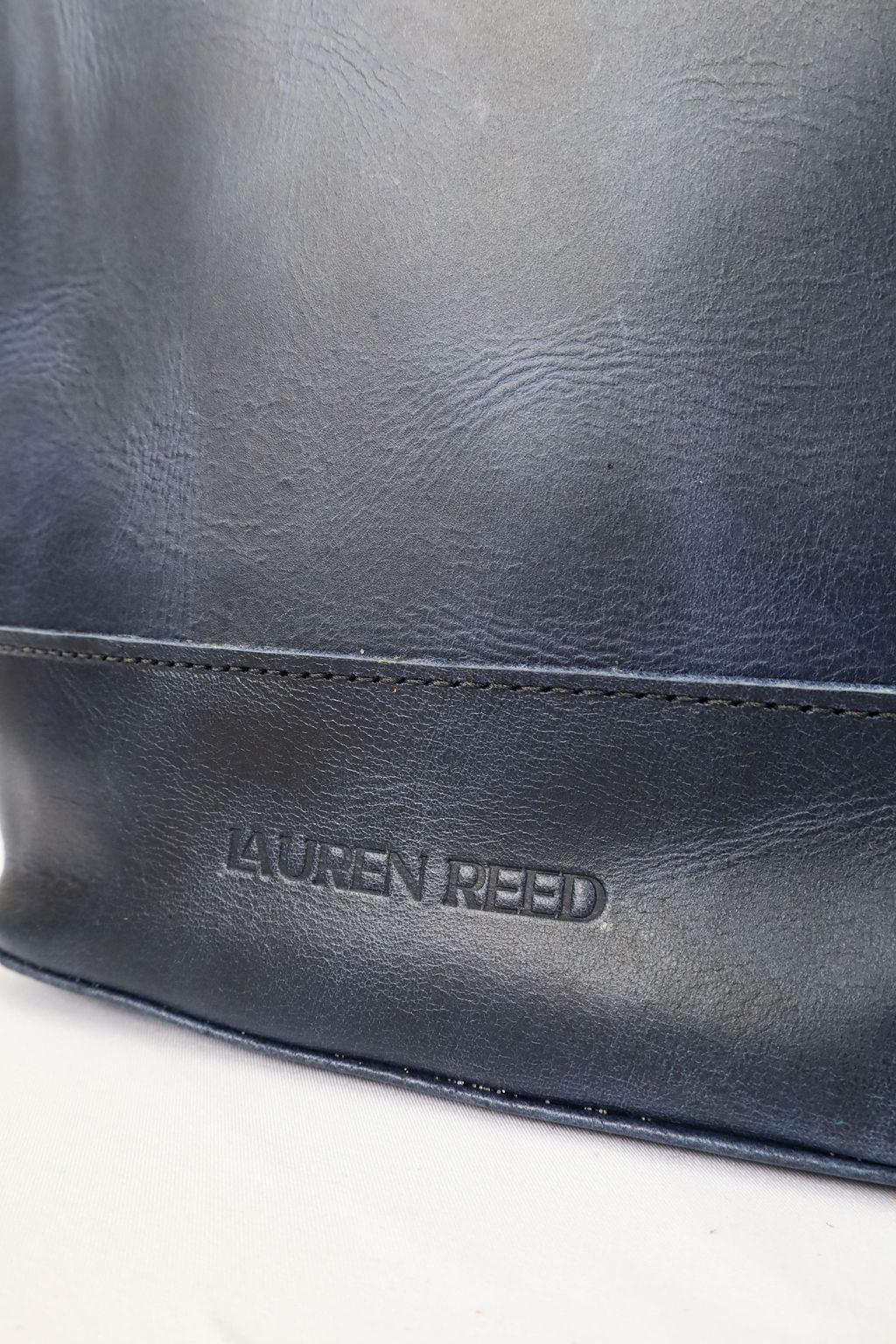Navy leather bag with Lauren Reed branding on a white background