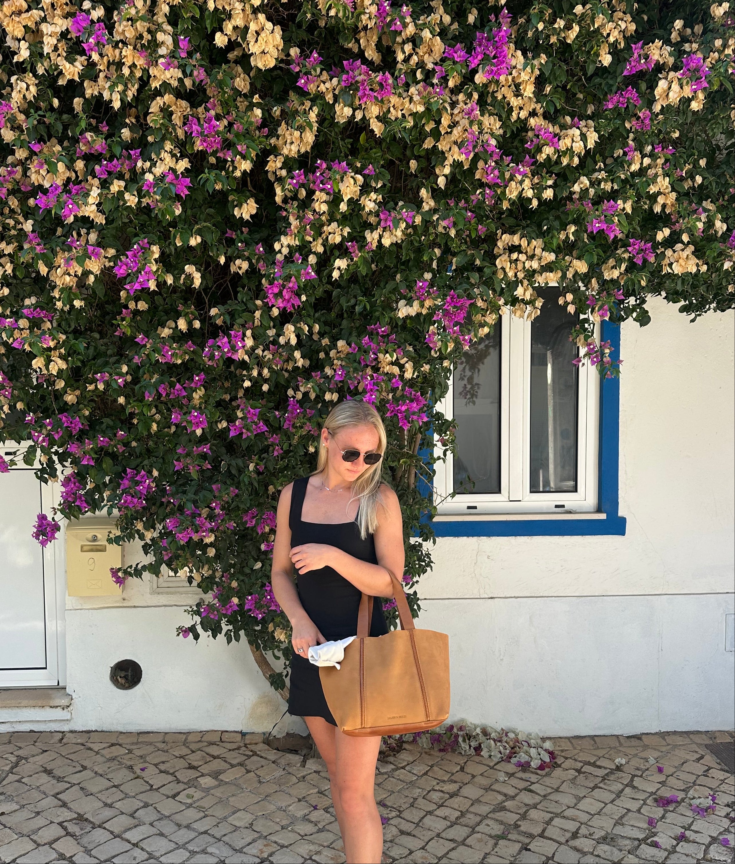 Woman standing in front of flowers with a Nubuck Leather Tote Bag