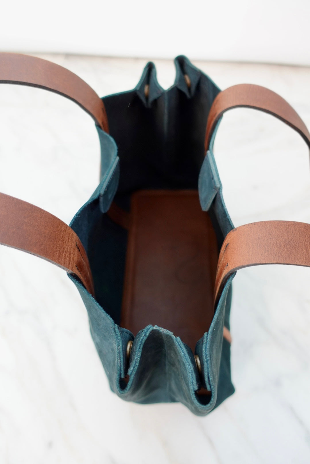 Blue leather bag with brown handles on a white background
