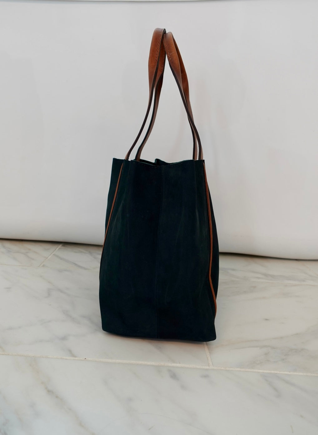 Blue tote bag with brown handles on a marble surface