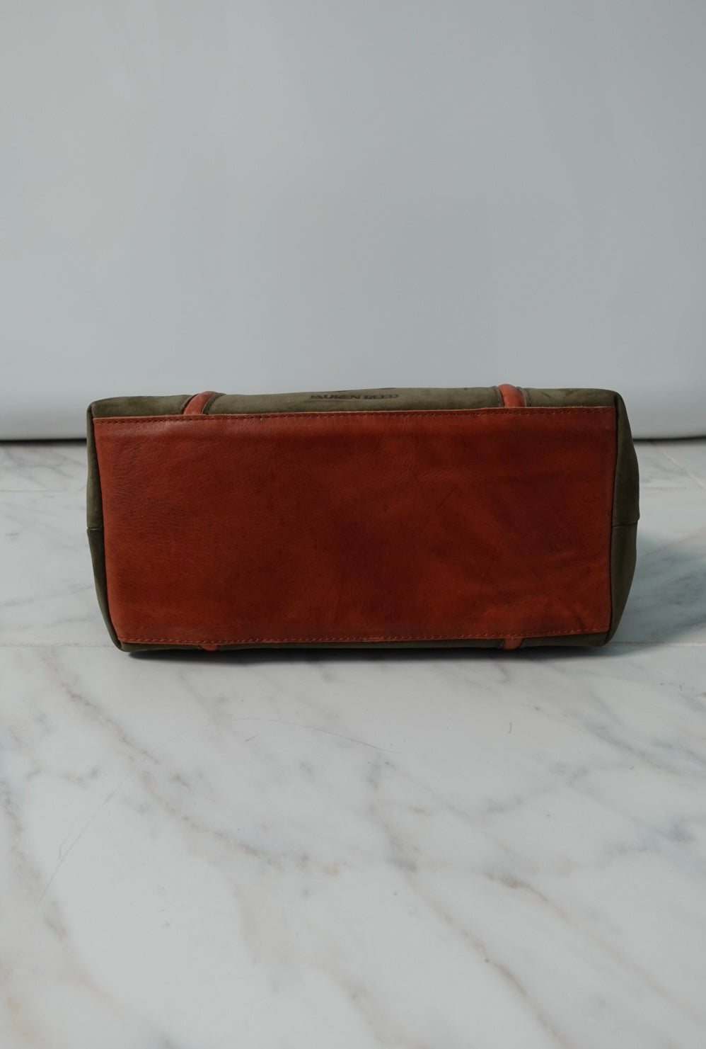 Green leather purse on a marble surface with a white background