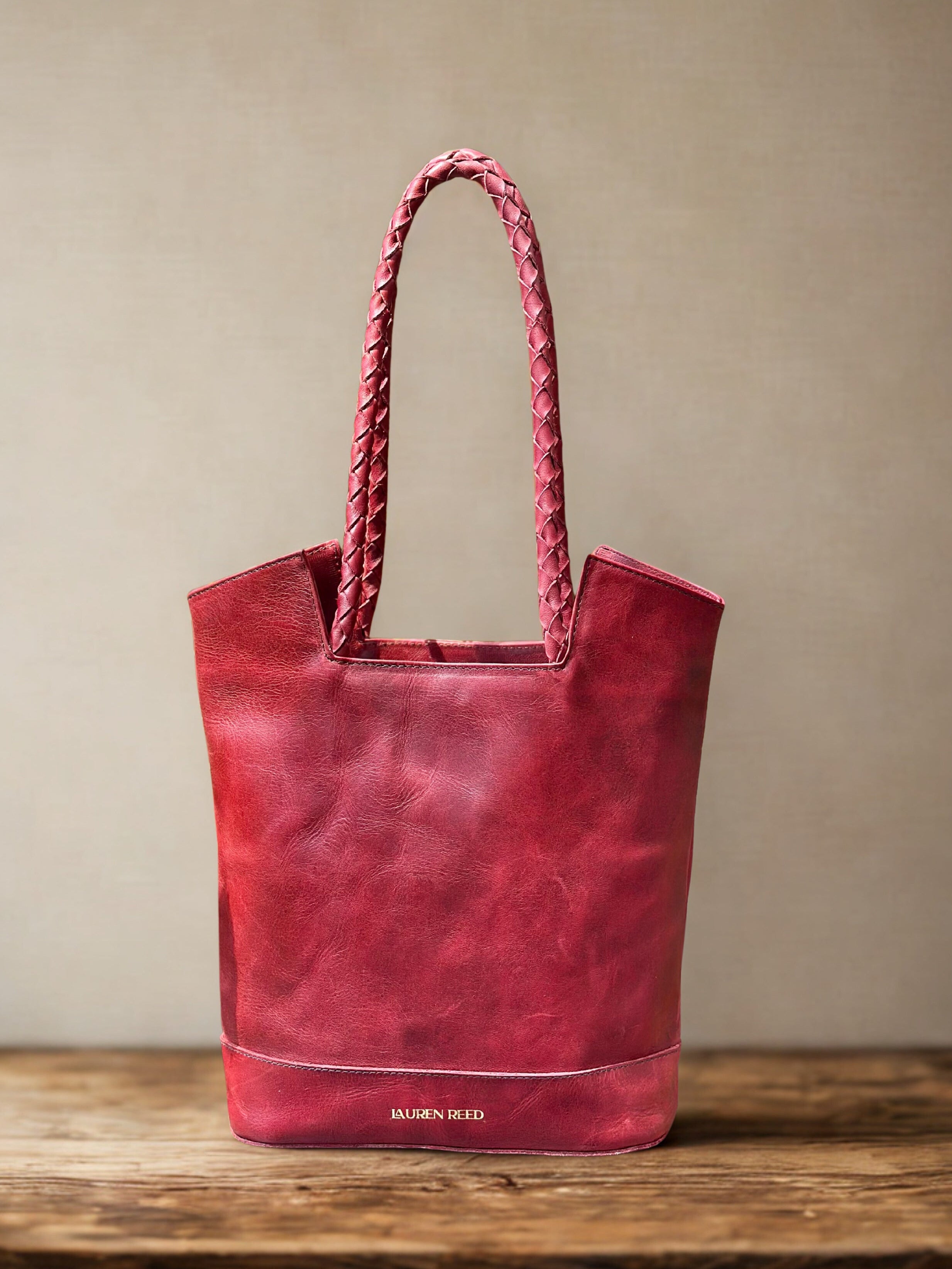 Red leather tote bag sitting on wooden table