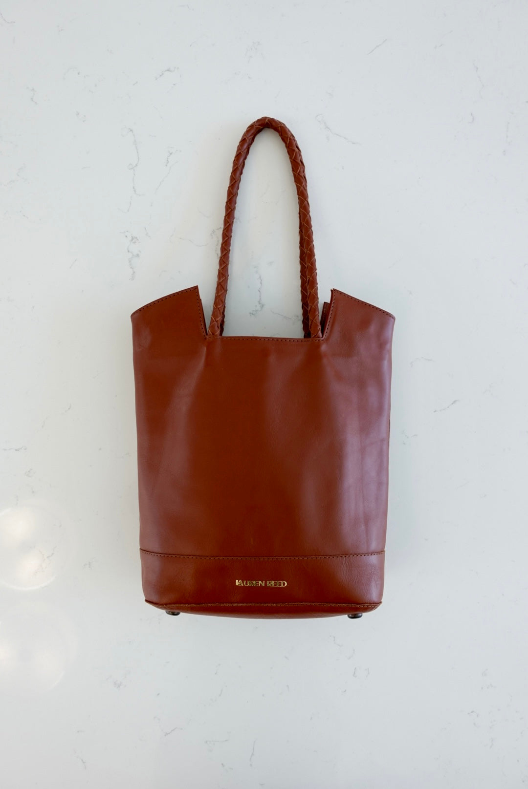 Saddle tan leather tote bag purse on marble