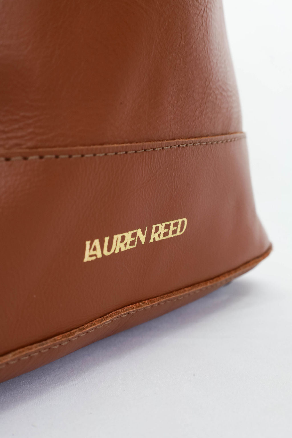 Brown leather bag with 'Lauren Reed' branding on a white background