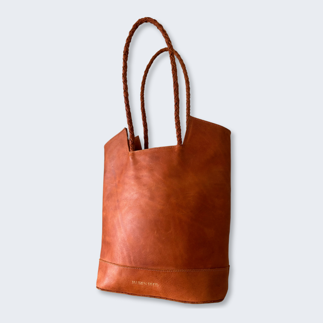 Tan leather tote bag with rope handles on a white background