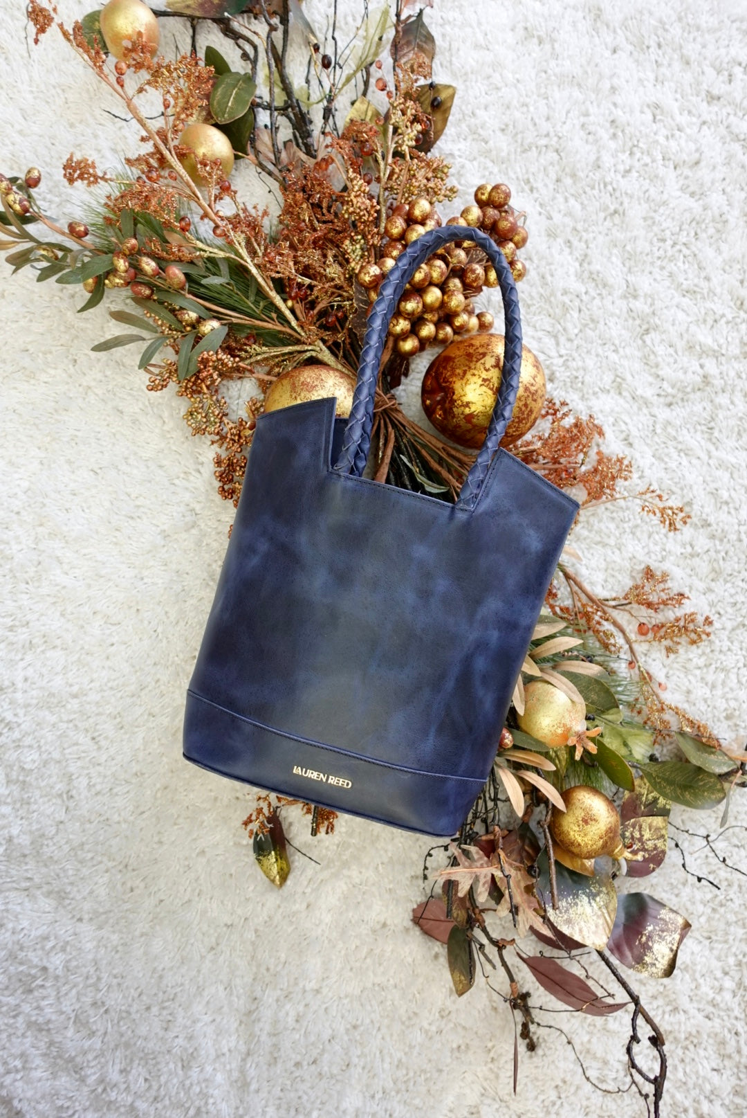 Blue leather tote bag with braided handles. 