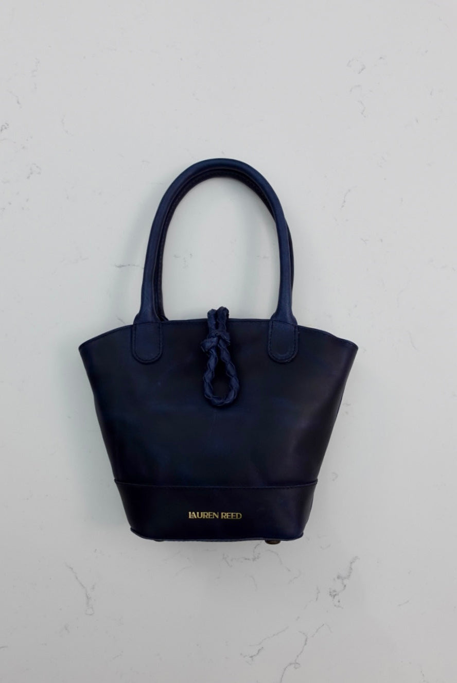 Navy blue handbag with a braided closure on a light gray background