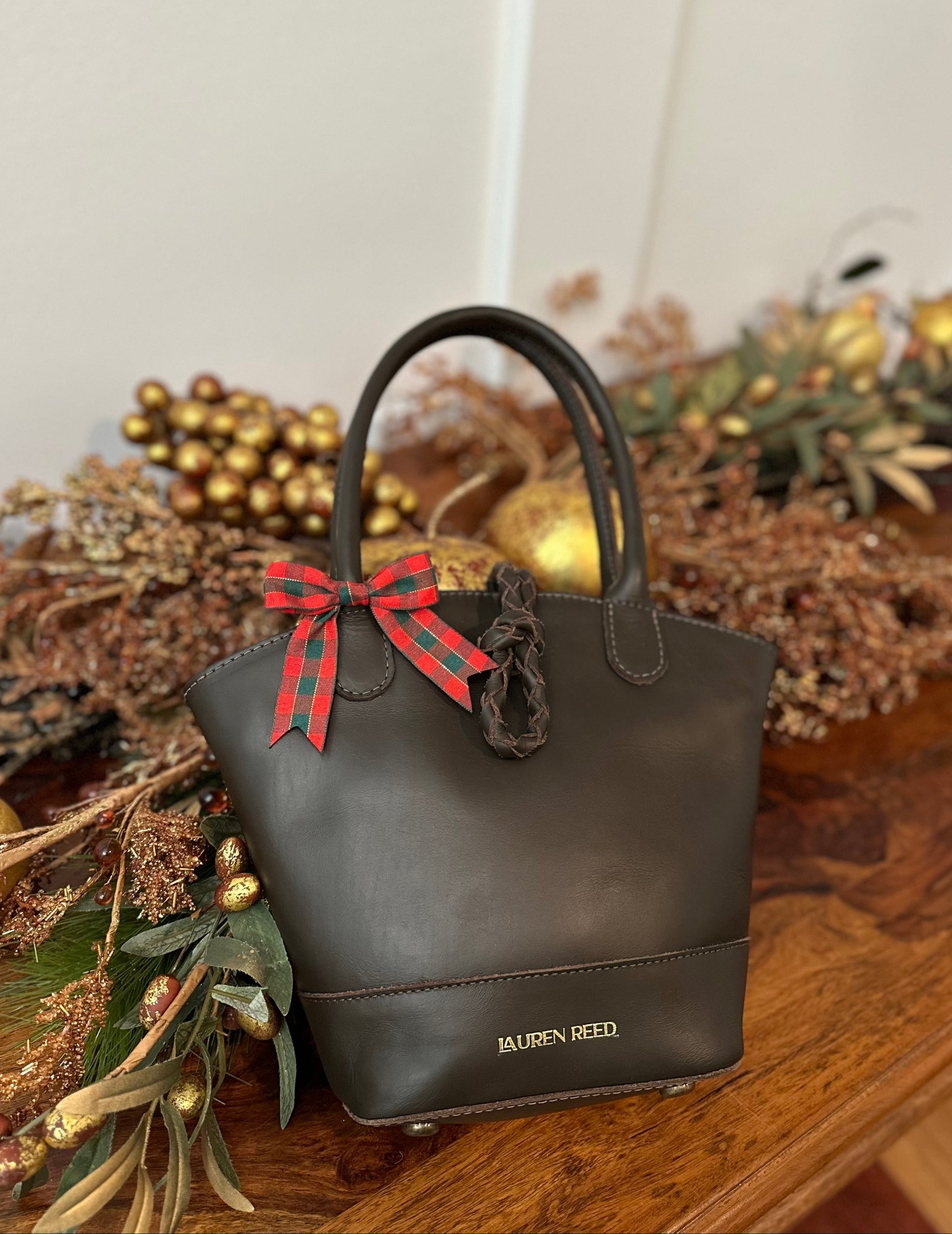 Brown handbag with a red bow on a wooden surface with decorative elements