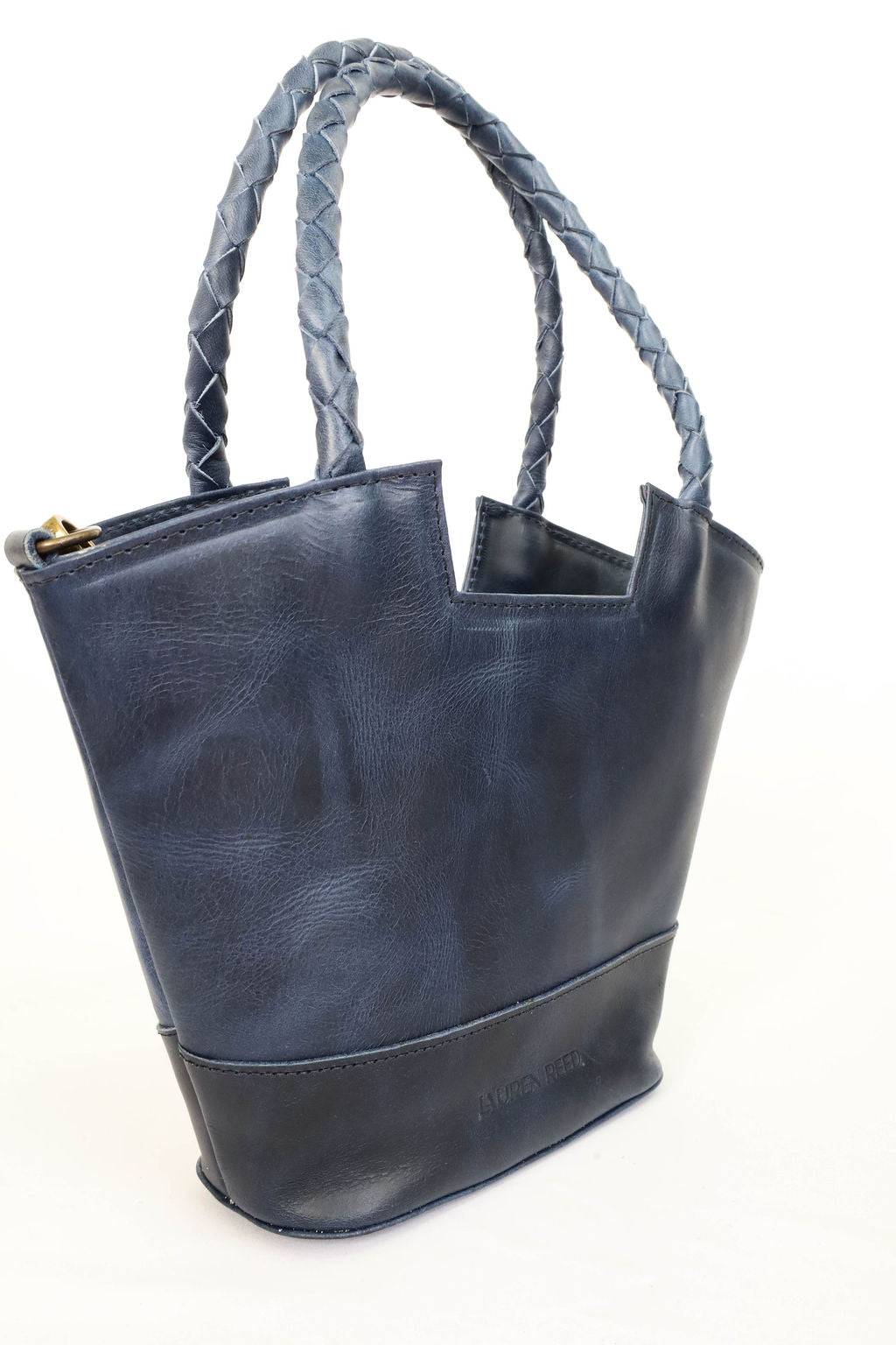 Blue leather tote bag with braided handle on a white background
