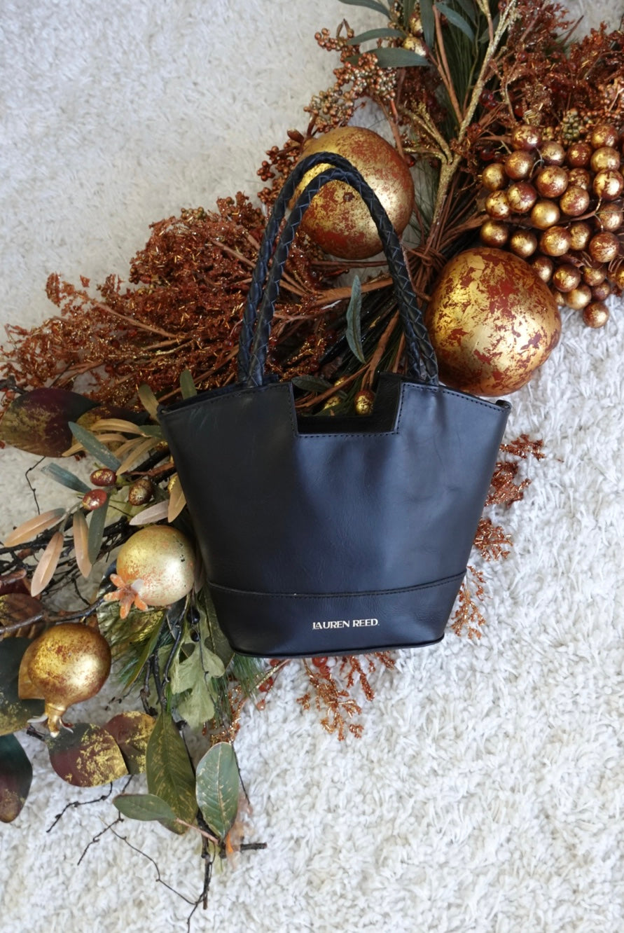 Black handbag with gold ornaments and leaves on a textured surface