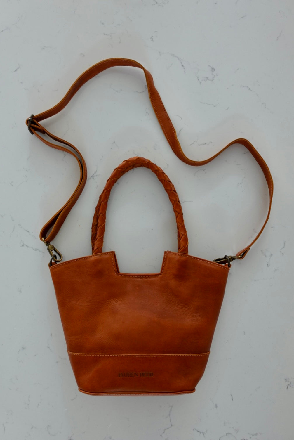 Brown leather handbag with a strap on a white background