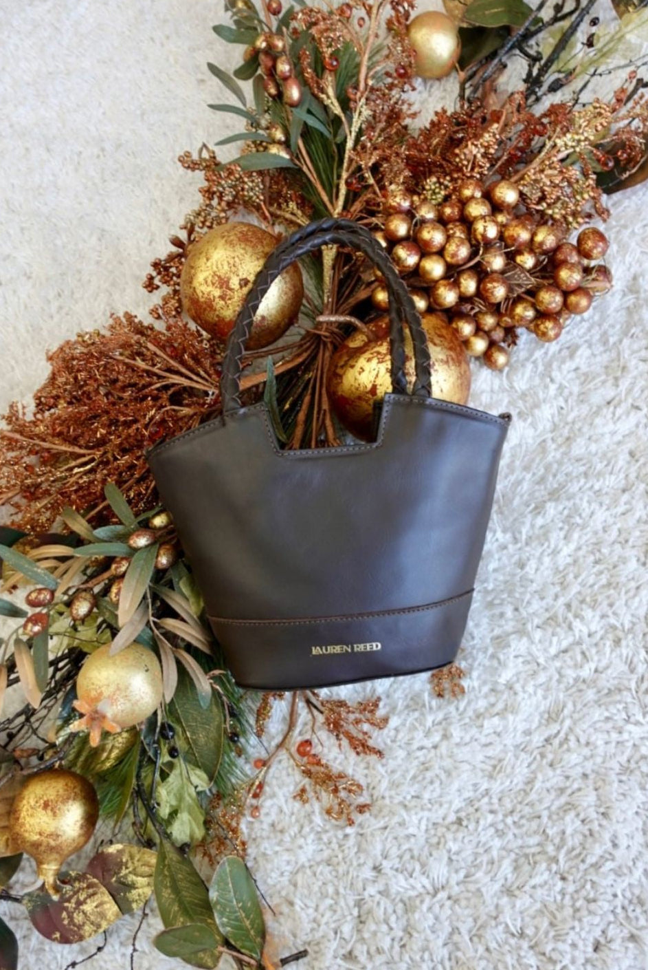 Brown leather handbag with gold accents on a decorative background 