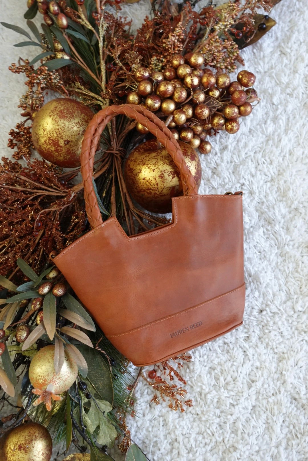 Tan leather handbag with gold ornaments on a textured surface
