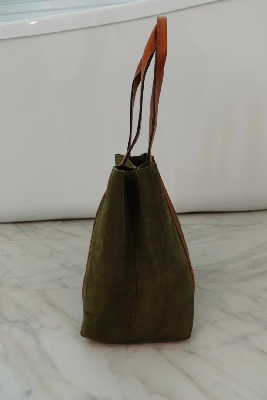 Green tote bag with brown handle on a marble surface