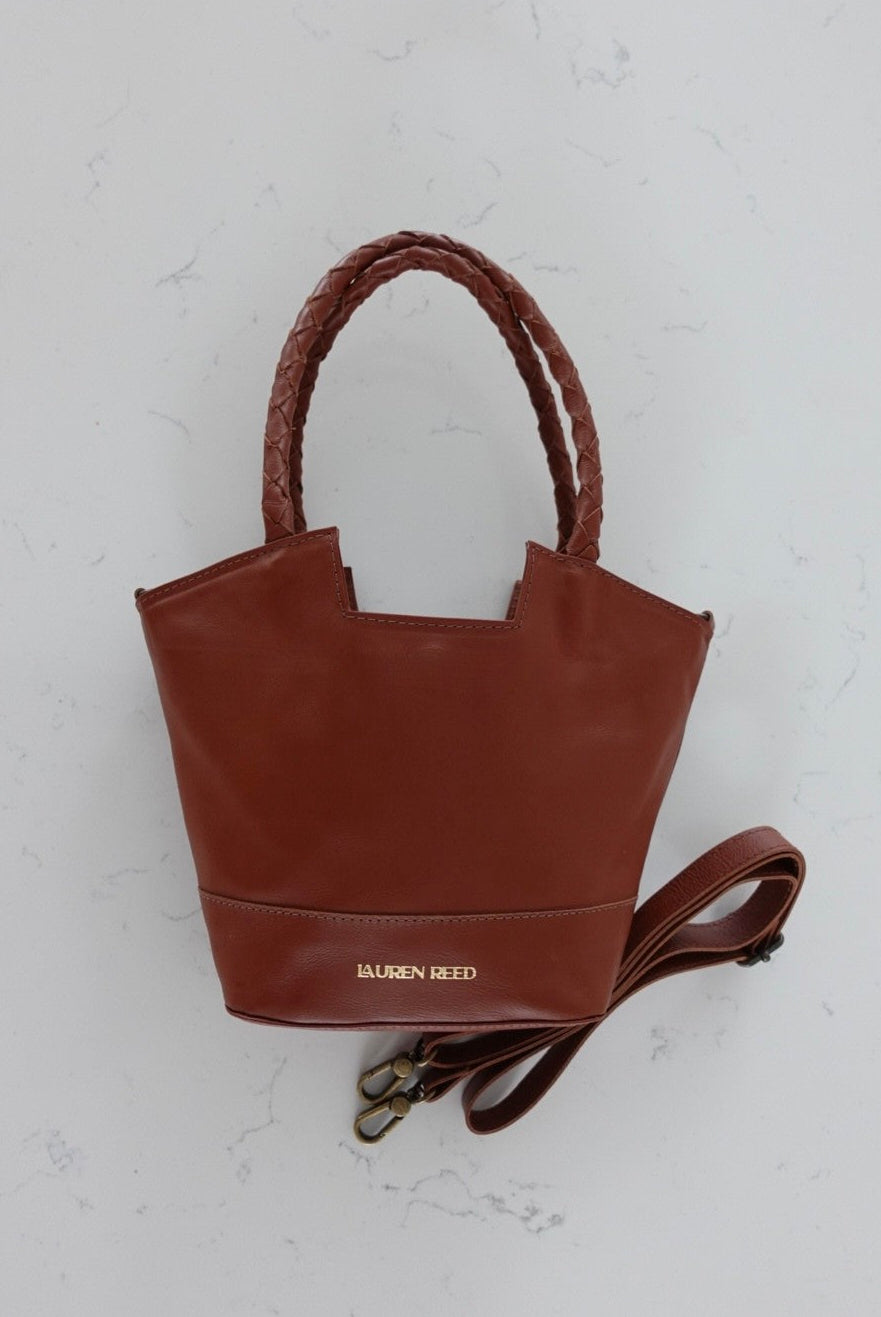 Brown leather Lauren Reed Co handbag with a strap on a light gray background